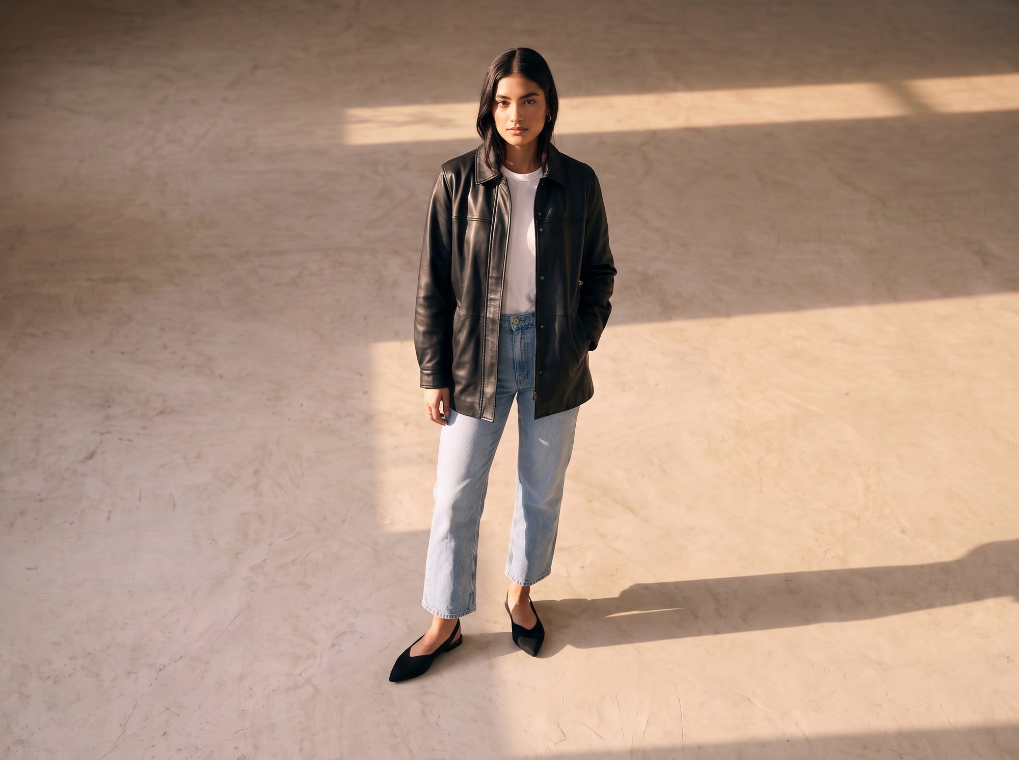 Full-body view of ALBA Minuit black knit slingback flats paired with light blue denim, white T-shirt and black leather jacket in soft natural light.