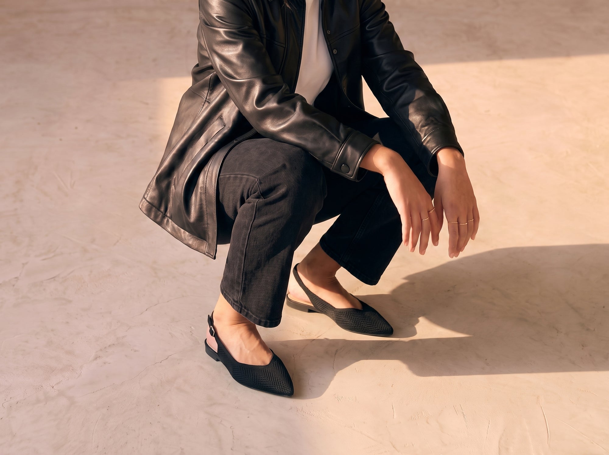 ALBA Minuit black knit slingback flats worn with black cropped jeans, a white tee shirt and a black leather jacket in warm natural light.