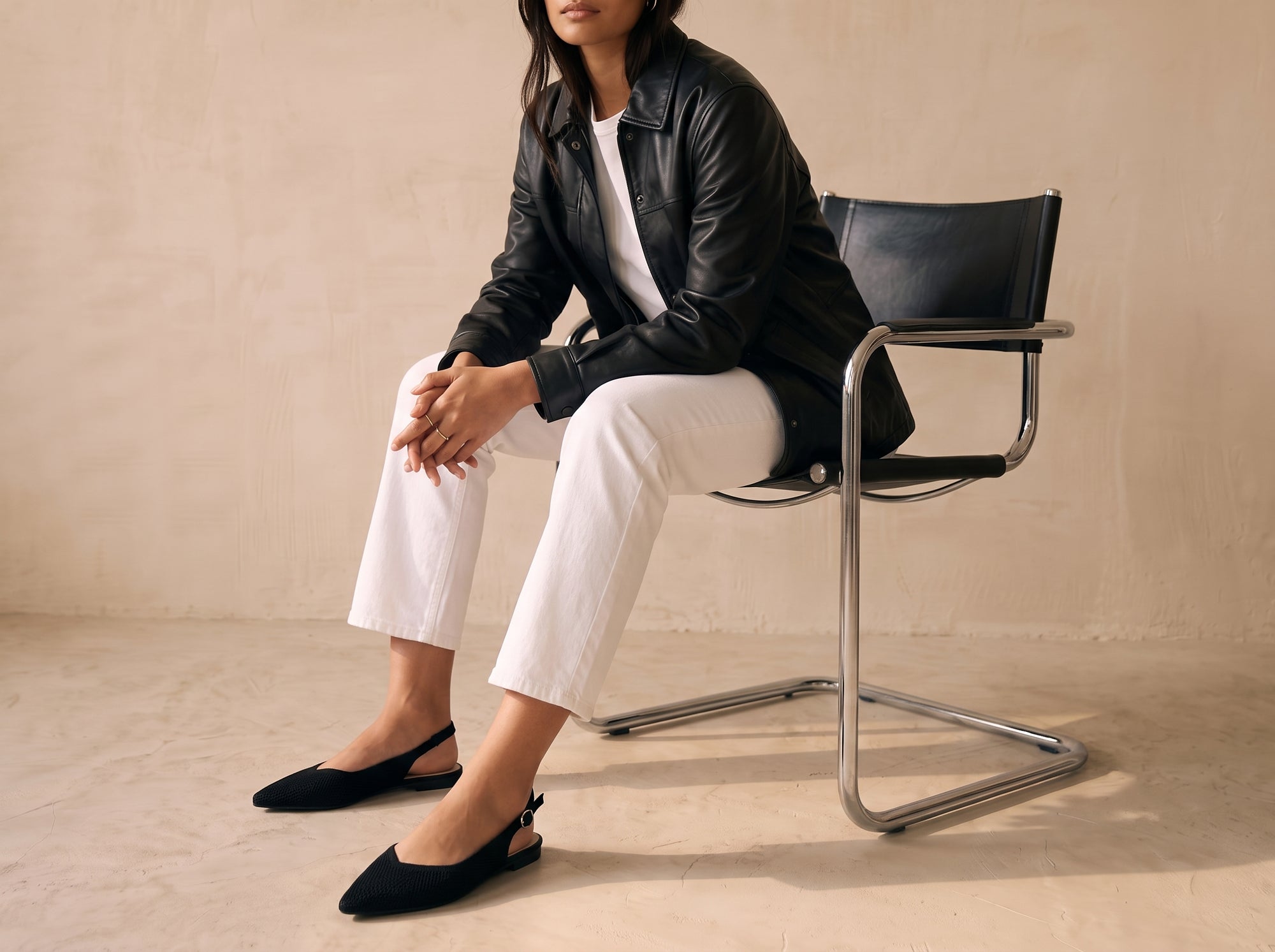 ALBA Minuit knit slingback flat styled with white cropped jeans, white T-shirt and black leather jacket while seated on a chrome chair